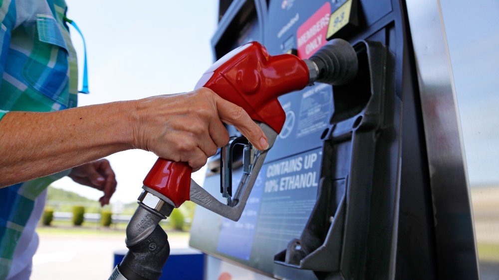 Image: A woman holds a nozzle as she refuels her car