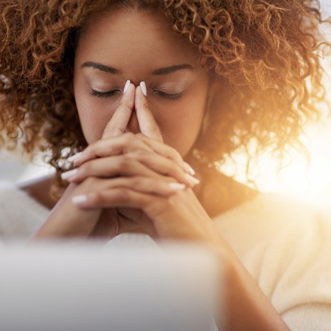 Image: A woman sits at her desk with eyes closed
