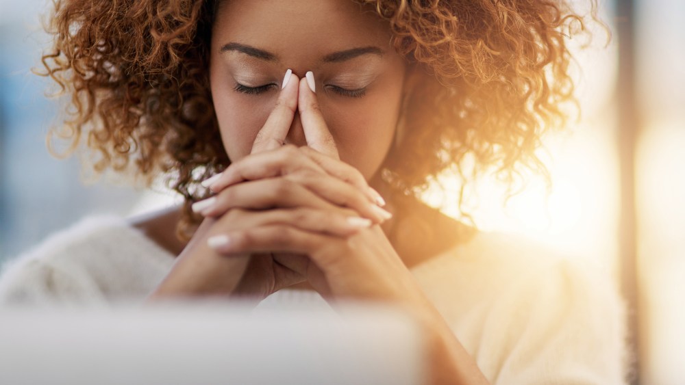Image: A woman sits at her desk with eyes closed