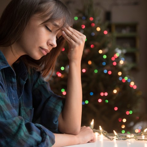 Image: A woman sits by a Christmas tree