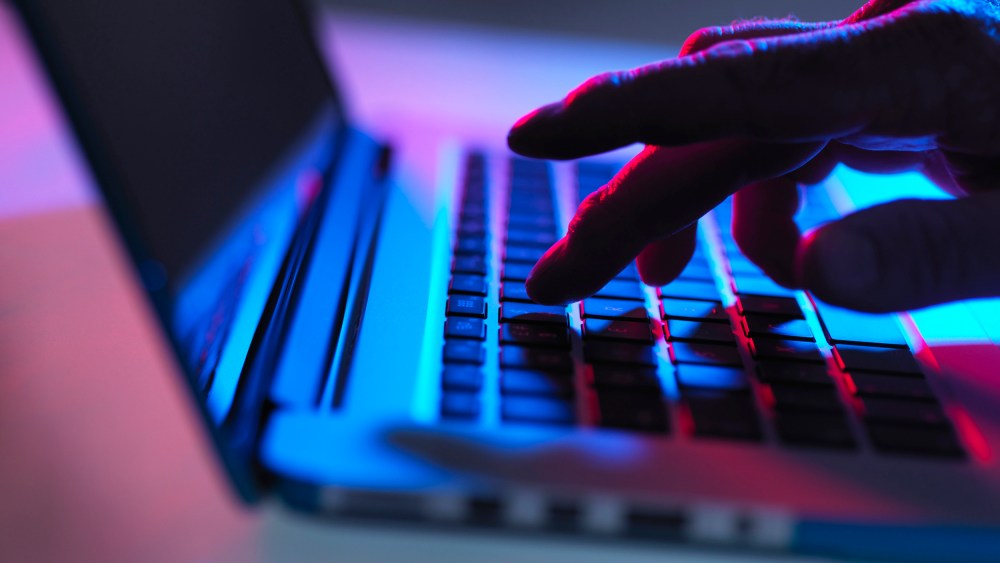 Image: A man types on a laptop keyboard