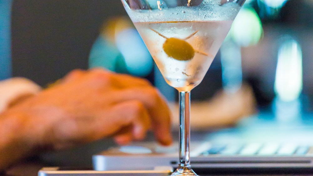Image: A man on a laptop with a martini