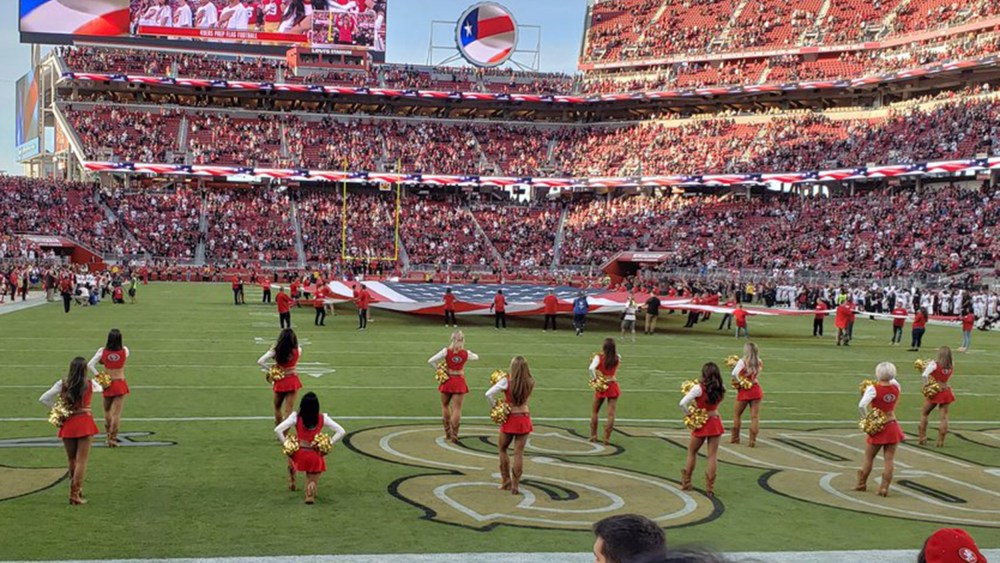Image: A San Francisco 49ers cheerleader kneels during the national anthem