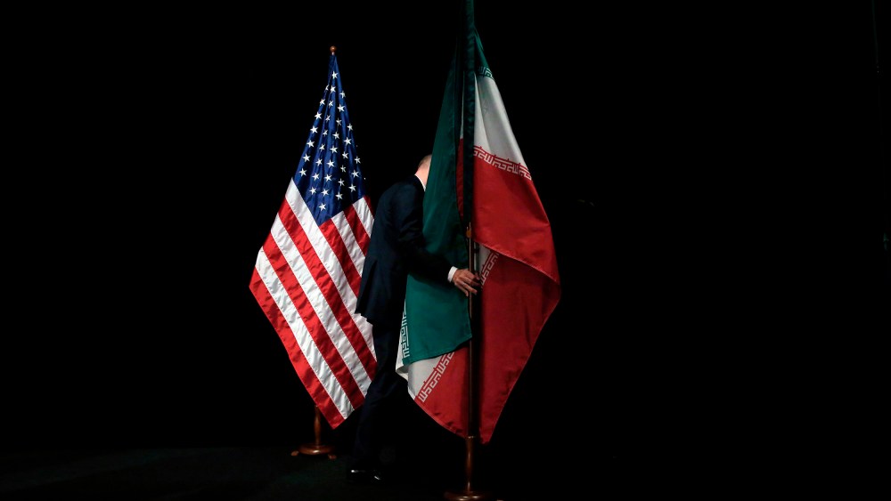 Image: A member of staff removes the Iranian flag from the stage after a group picture with foreign ministers and representatives of United States, Iran, China, Russia, Britain, Germany, France and the European Union