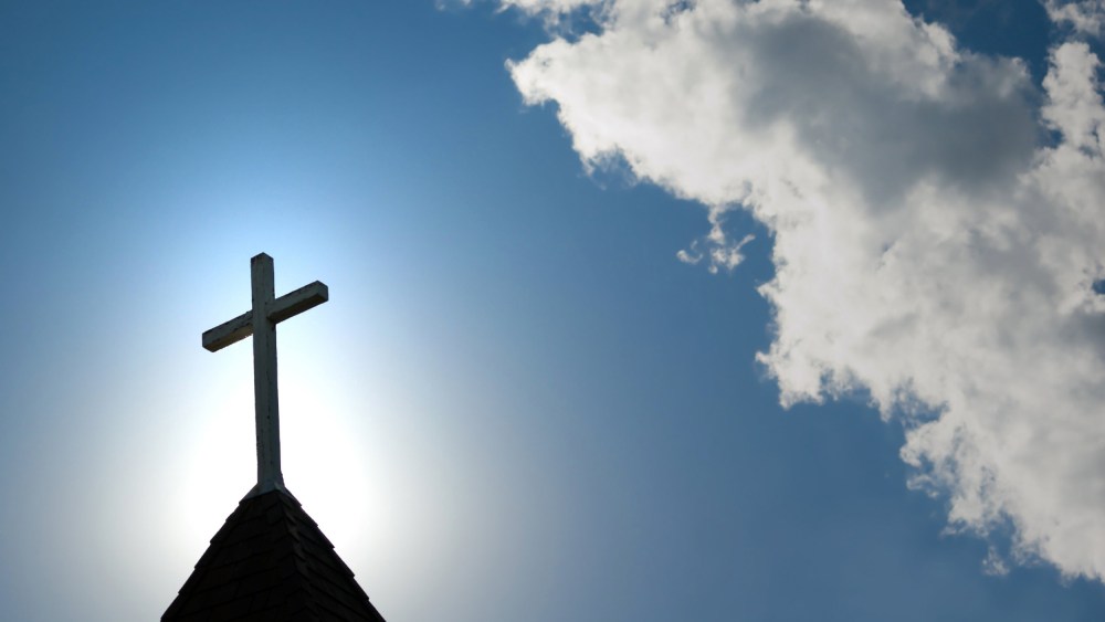 Image: Easter morning with the sun behind a church steepl cross.