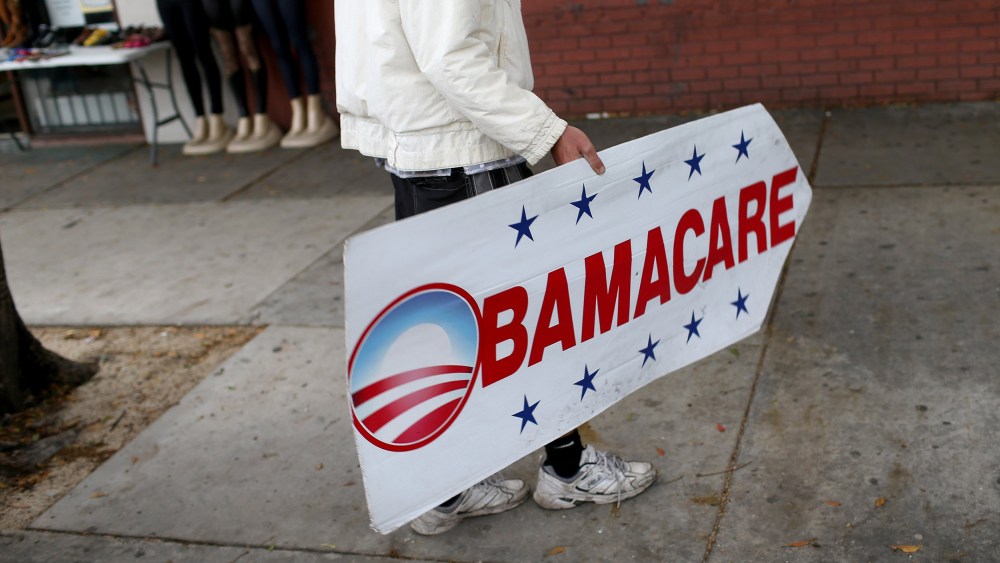 Image: Pedro Rojas holds a sign directing people to an insurance company where they can sign up for the Affordable Care Act, also known as Obamacare