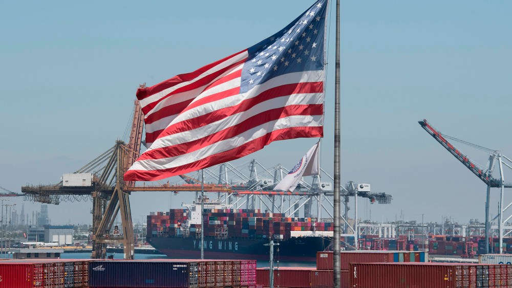 Image: The U.S. flag flies over a container ship unloading it's cargo from Asia, at the Port of Long Beach, California