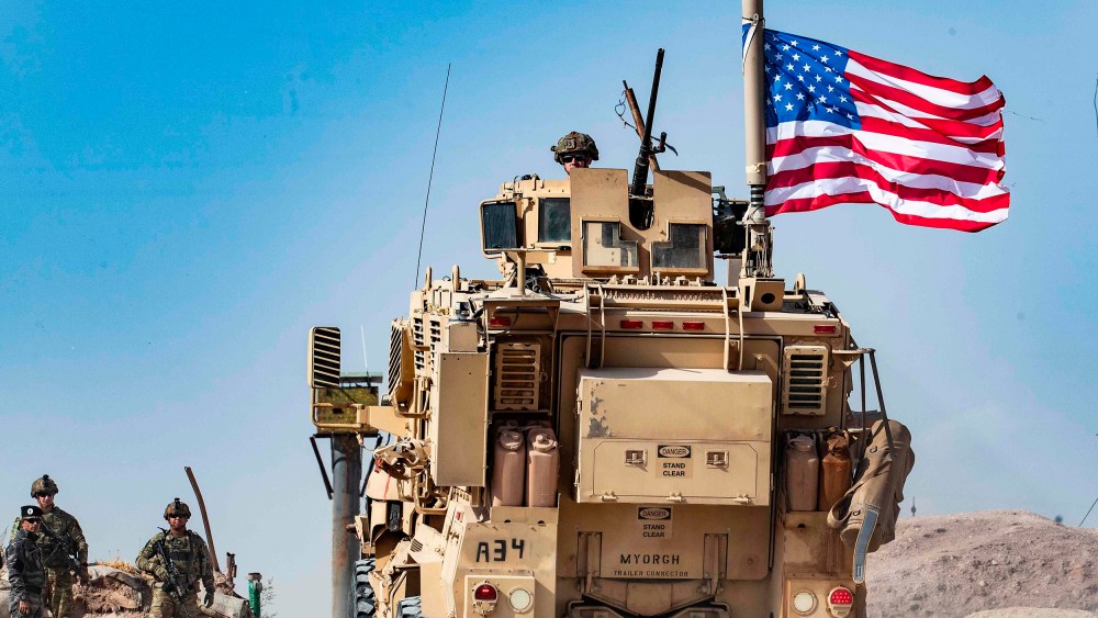Image: A U.S. soldier sits atop an armoured vehicle during a demonstration by Syrian Kurds against Turkish threats at a US-led international coalition base on the outskirts of Ras al-Ain town in Syria's Hasakeh province near the Turkish border