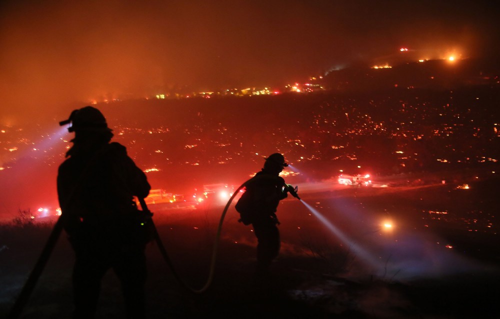 Image: Firefighters walk to the fire line at the Lilac fire in Bonsall, California.