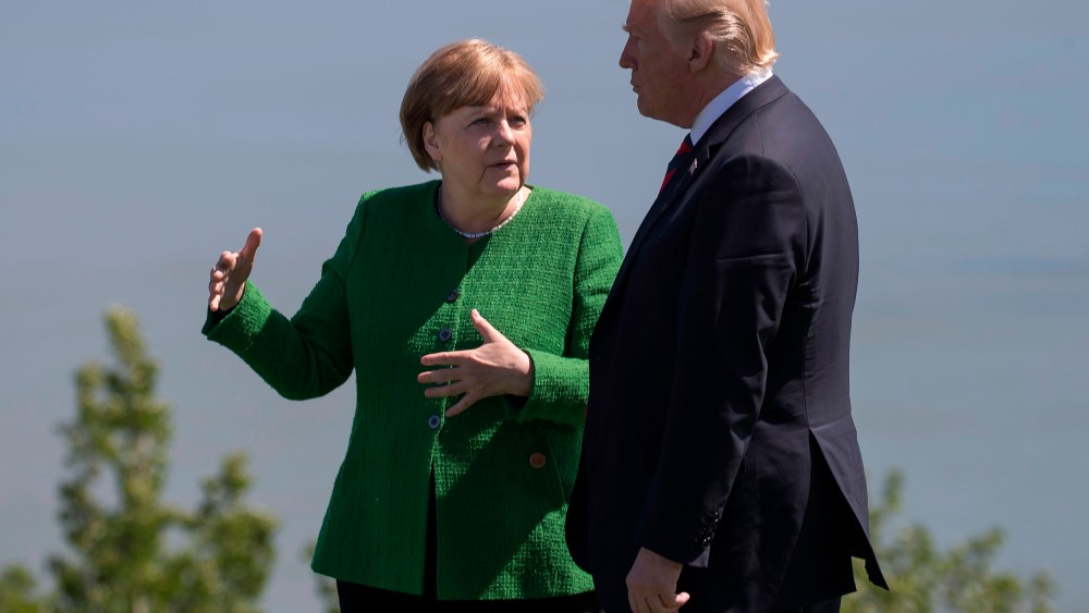 Image: German Chancellor Angela Merkel confers with US President Donald Trump following the family photo session during the G7 Summit in La Malbaie, Canada