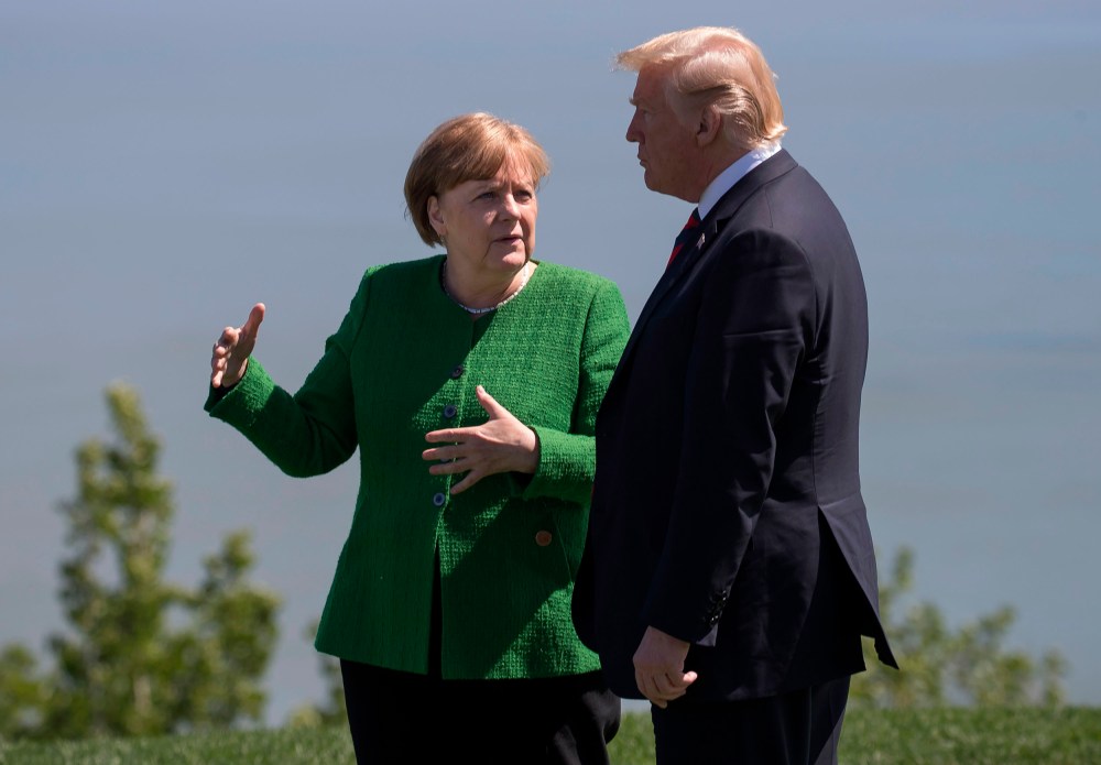 Image: German Chancellor Angela Merkel confers with US President Donald Trump following the family photo session during the G7 Summit in La Malbaie, Canada