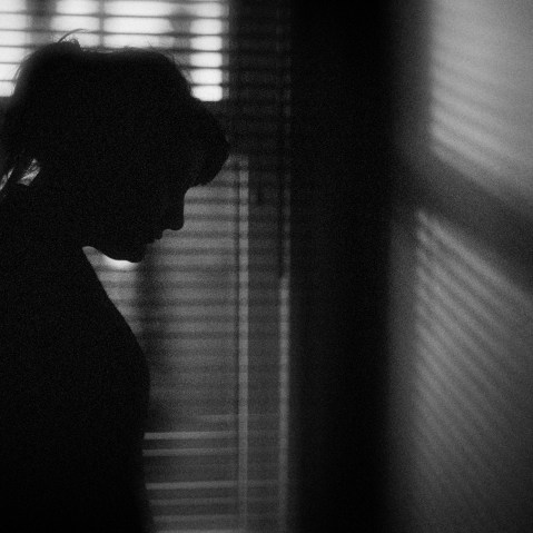 Image: The silhouette of a woman standing by a window.