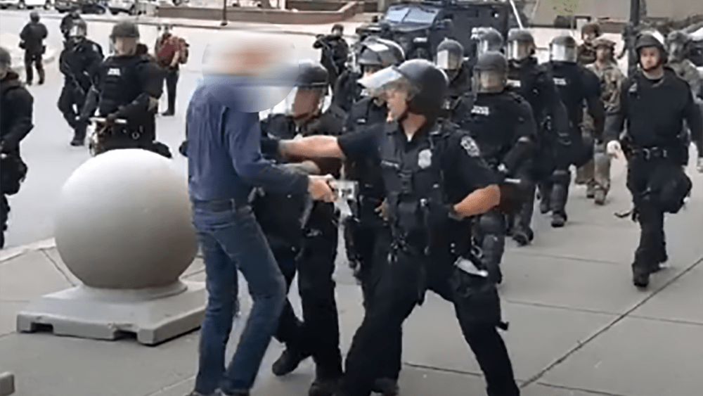 Image: In this screenshot from video, WBFO reporter records graphic video of incident showing an officer appear to push an individual leaving him stumbling to a fall in Niagra Square, Buffalo.