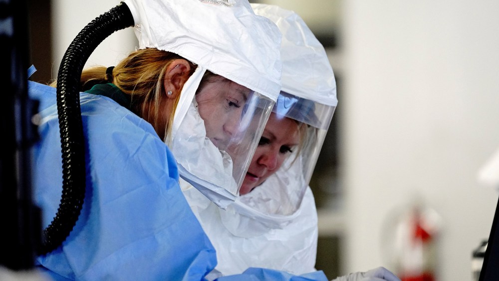 Image: Healthcare workers wearing powered air purifying respirator (PAPR) hoods process COVID-19 test samples at a drive-thru testing site operated by Avera Health inside the former Silverstar Car Wash, Sioux Falls