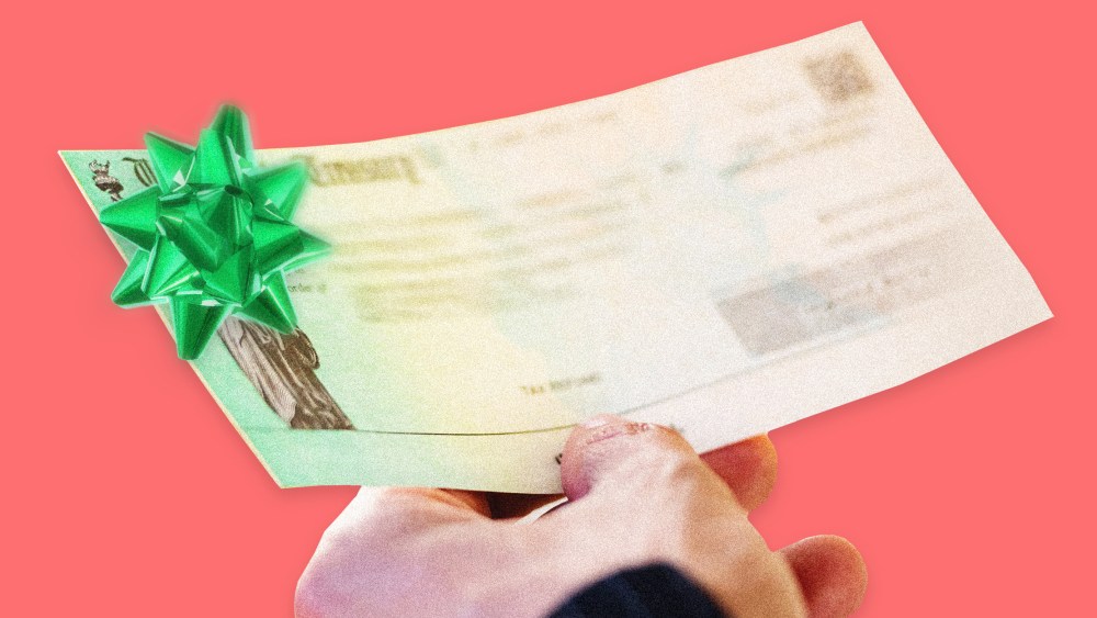 Image: A person holds a U.S. Treasury Check with a green Christmas bow on it.
