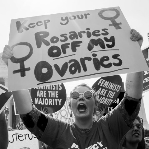 Image: Pro-choice activist holds sign that reads,"Keep your rosaries off my ovaries".