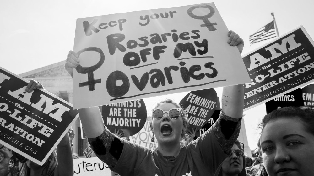 Image: Pro-choice activist holds sign that reads,"Keep your rosaries off my ovaries".