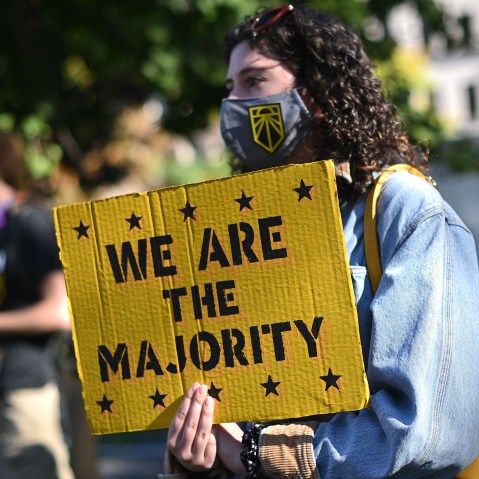 Image: A girl holds a yellow placard that reads,"We are the majority".