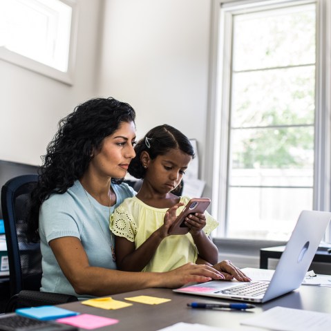 Daughter sitting in working mothers lap