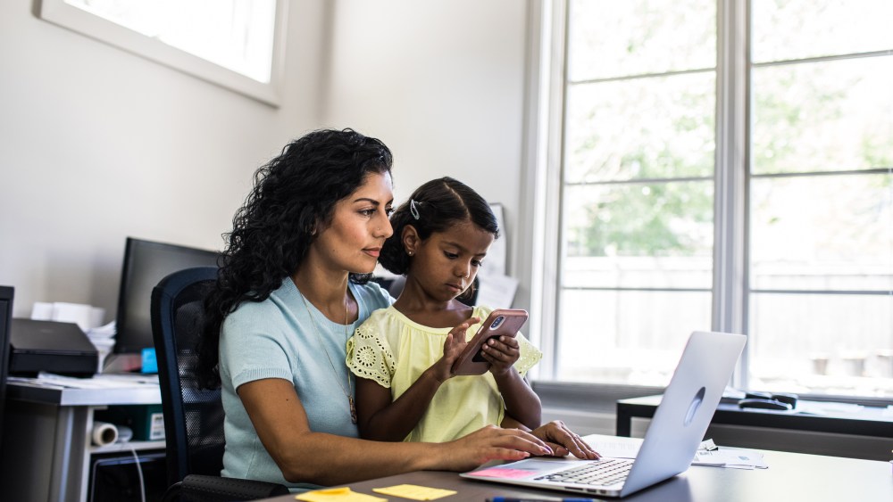 Daughter sitting in working mothers lap
