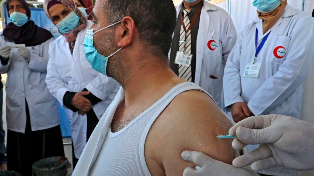 Image: A Palestinian health worker gets vaccinated against COVID-19.