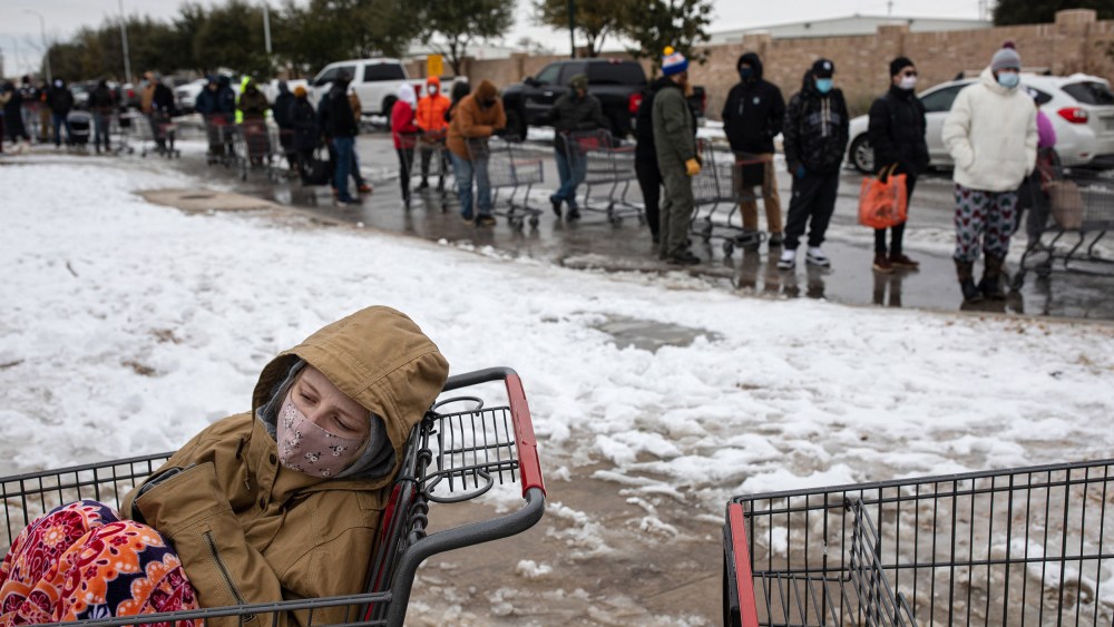 Image: A girl sits in a shopping cart waiting in a long line to enter a grocery store in Austin, Texas.