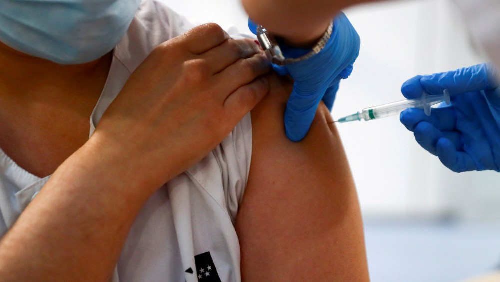 Image: Health worker receives a dose of the Pfizer-BioNTech COVID-19 vaccine