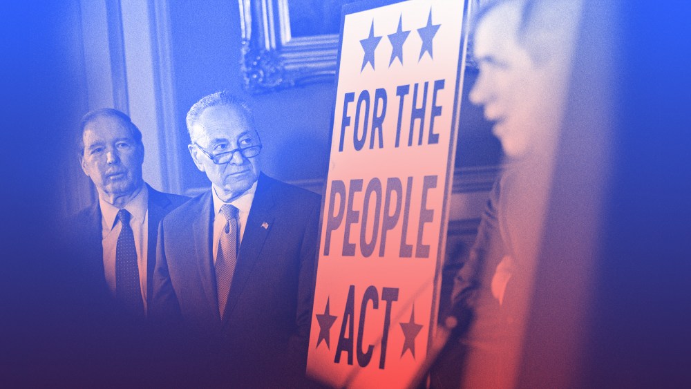 Image: Chuck Schumer stands next to a board that reads,"For the People Act".
