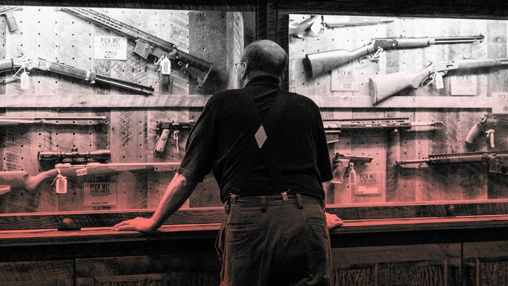IMage: A man looks at a case of firearms at the National Rifle Association convention in Indianapolis in 2019.