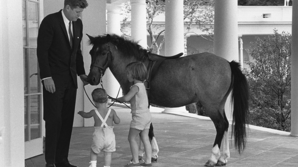 Image; Outside of the Oval Office, President John F. Kennedy and his children, John and Caroline, play with their pet pony, Macaroni, in 1962.