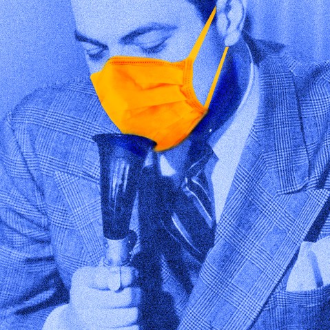 Photo illustration: A person wearing a suit and a protective mask speaking into a dictaphone.
