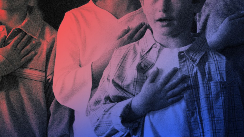 Image of students with hands over their hearts reciting the pledge of allegiance.