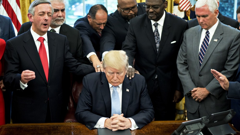 Then-President Donald Trump bows his head during a prayer while surrounded by then-Vice President Mike Pence, faith leaders and evangelical ministers after signing a proclamation declaring a day of prayer in the White House on Sept. 1, 2017.