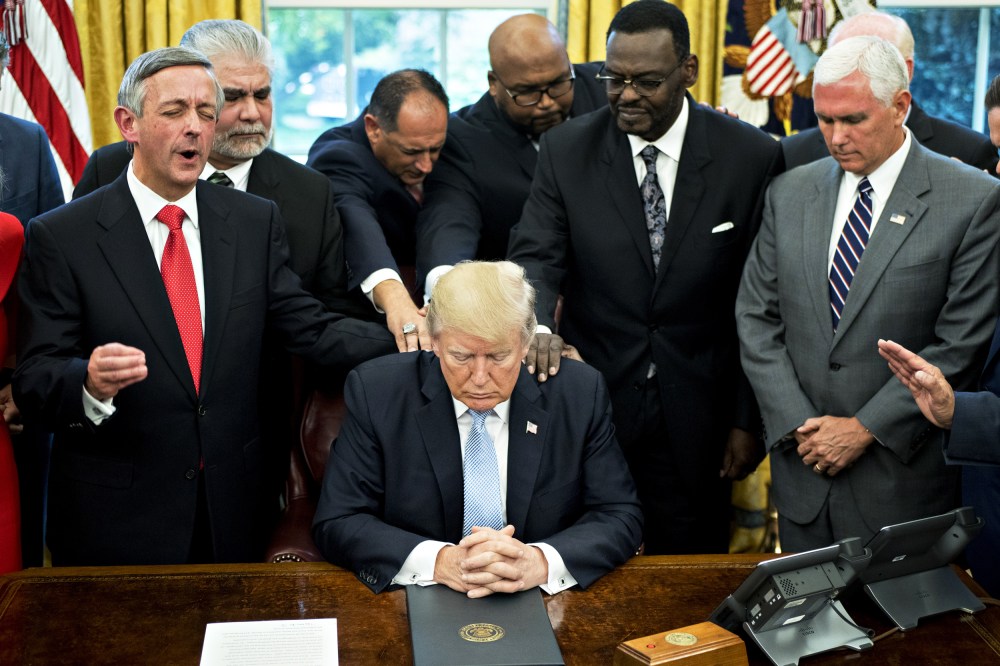Then-President Donald Trump bows his head during a prayer while surrounded by then-Vice President Mike Pence, faith leaders and evangelical ministers after signing a proclamation declaring a day of prayer in the White House on Sept. 1, 2017.