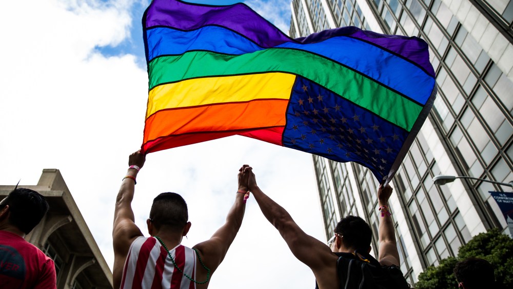 Image: A couple hold up a gay pride flag.