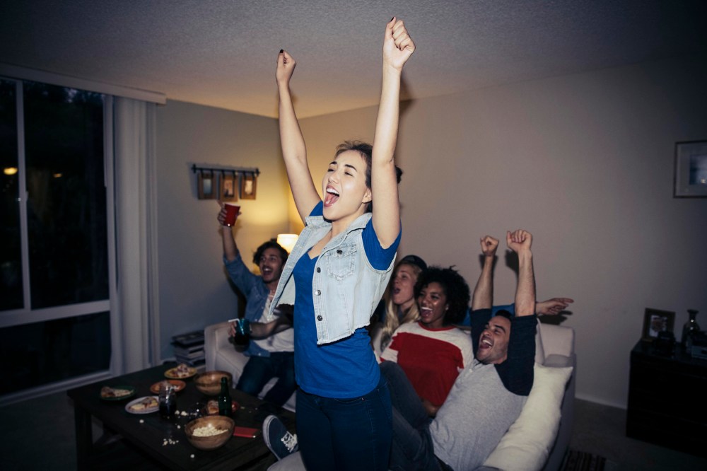 Friends cheering while watching sports on TV at home