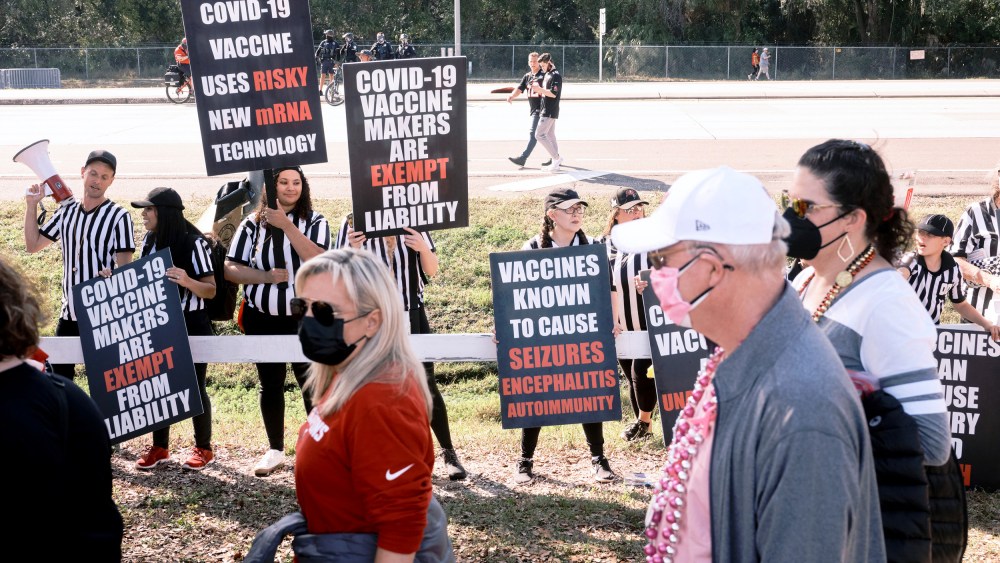 Image: Anti-vaccine protesters shout and wave signs as health care workers wait to enter the Raymond James Stadium before the Super Bowl in Tampa, Fla., on Feb. 7, 2021.
