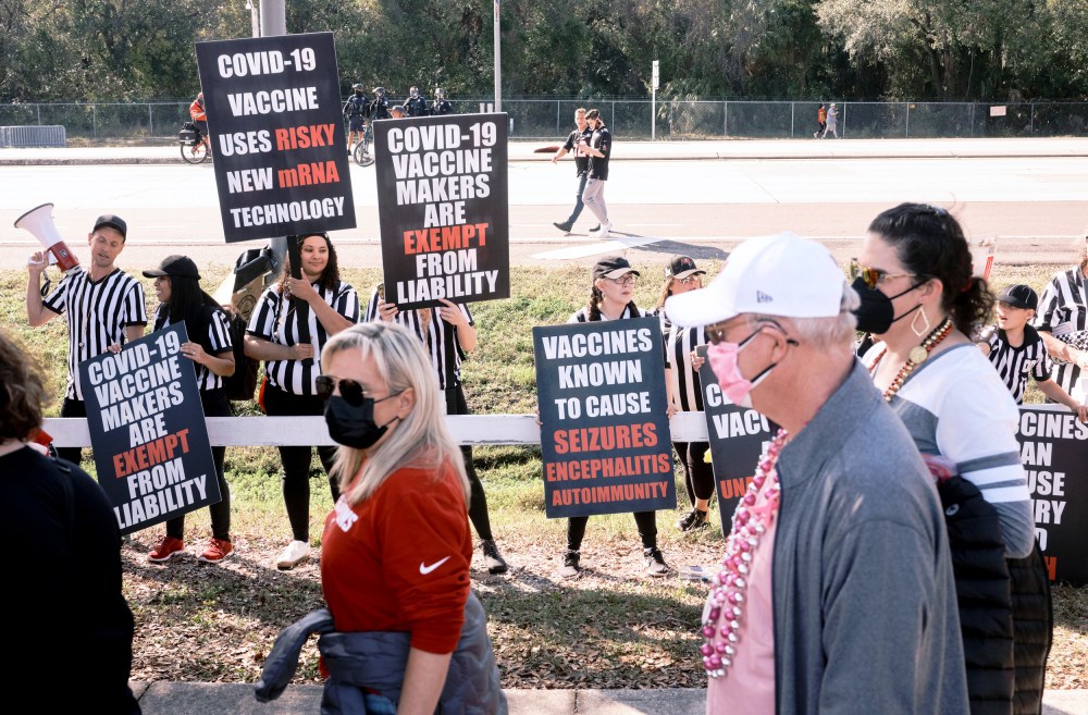 Image: Anti-vaccine protesters shout and wave signs as health care workers wait to enter the Raymond James Stadium before the Super Bowl in Tampa, Fla., on Feb. 7, 2021.