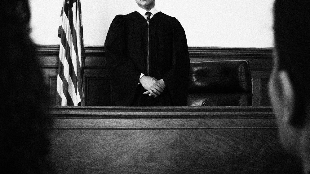 Image: Judge standing in front of defendants and lawyers