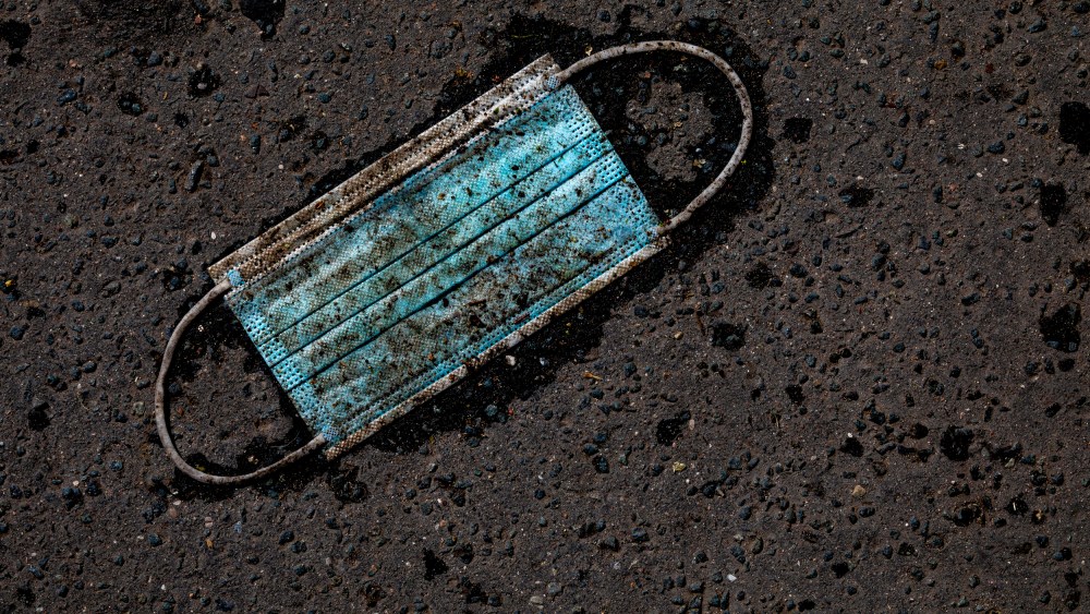 IMage: A discarded surgical mask on an asphalt street.