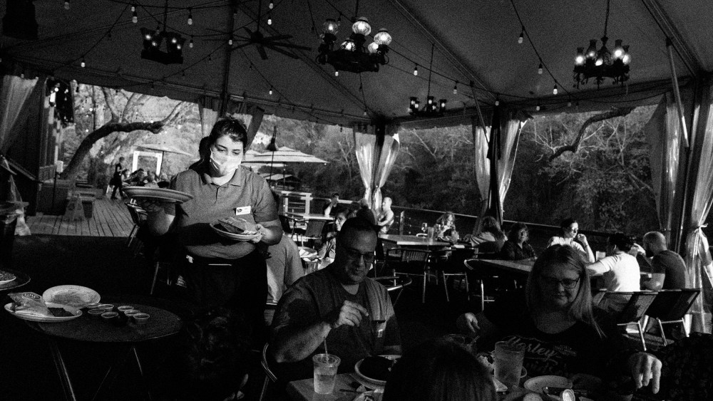 Image; A server at the County Line in Austin, Texas, serves food to customers on April 5, 2021.