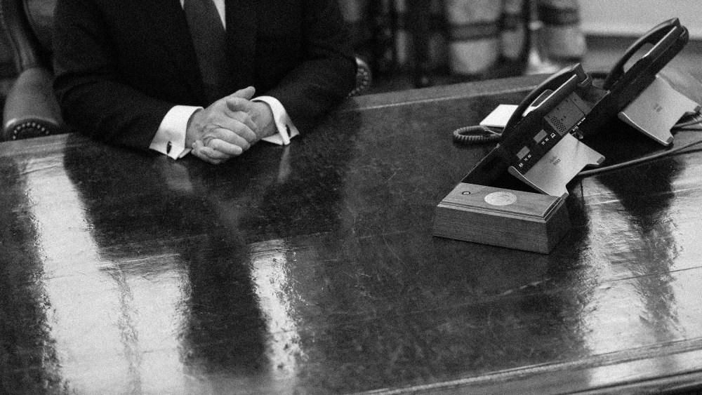 Image: Then-President Donald Trump is reflected on the Resolute Desk in the Oval Office at the White House in 2019.