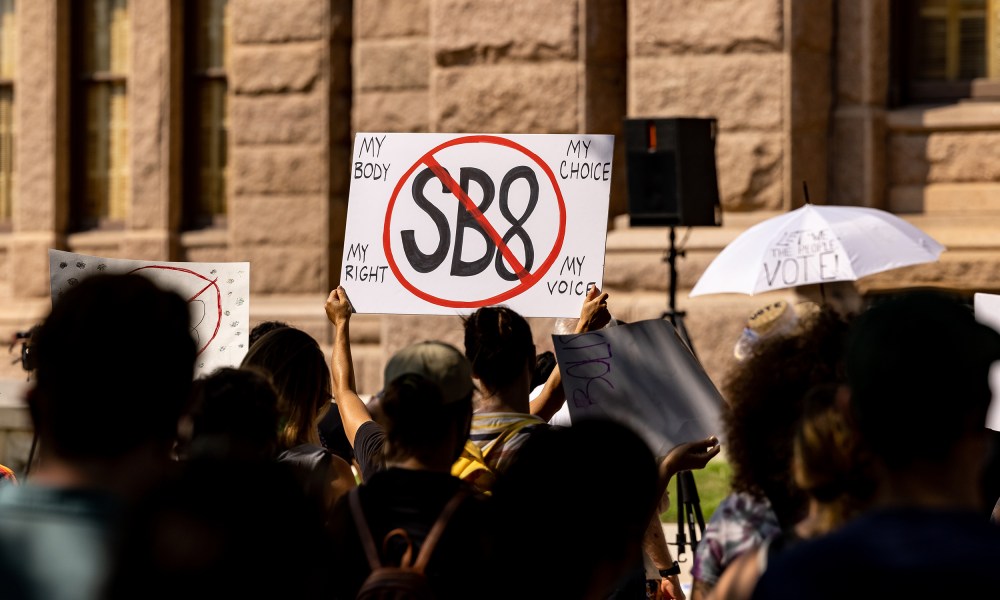 Image: Protestors hold up a sign that has a stop sign over the text,"SB8".