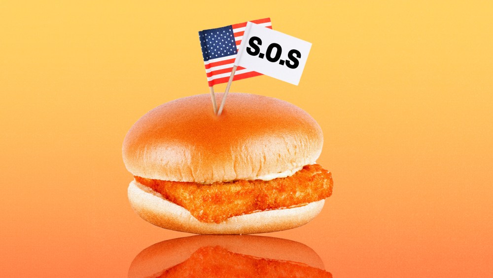 Photo illustration: A fish burger with two small paper flags, one is an American flag and the other is a white flag that reads,"S.O.S."