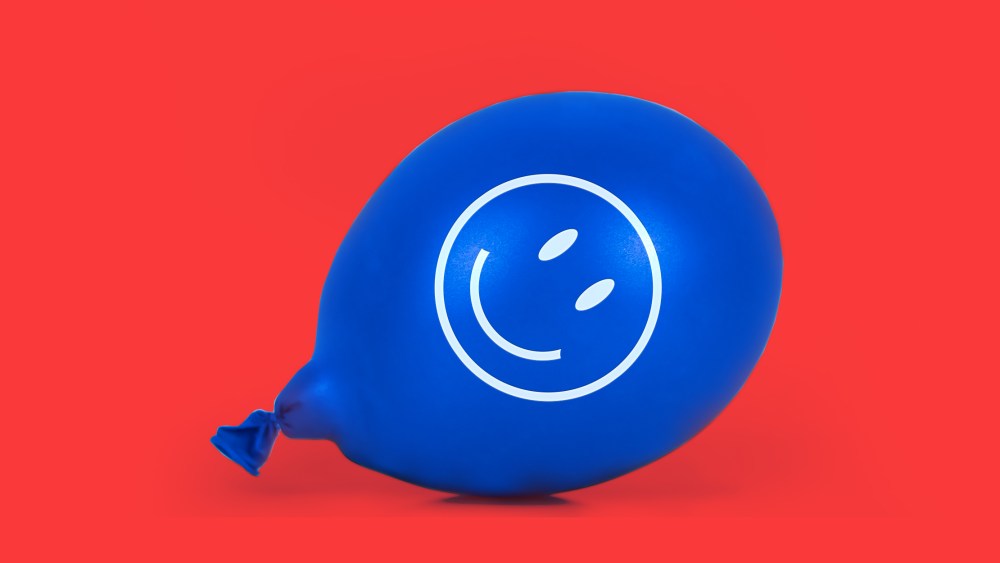 Photo illustration: A blue balloon with a smiley face lying on the floor.