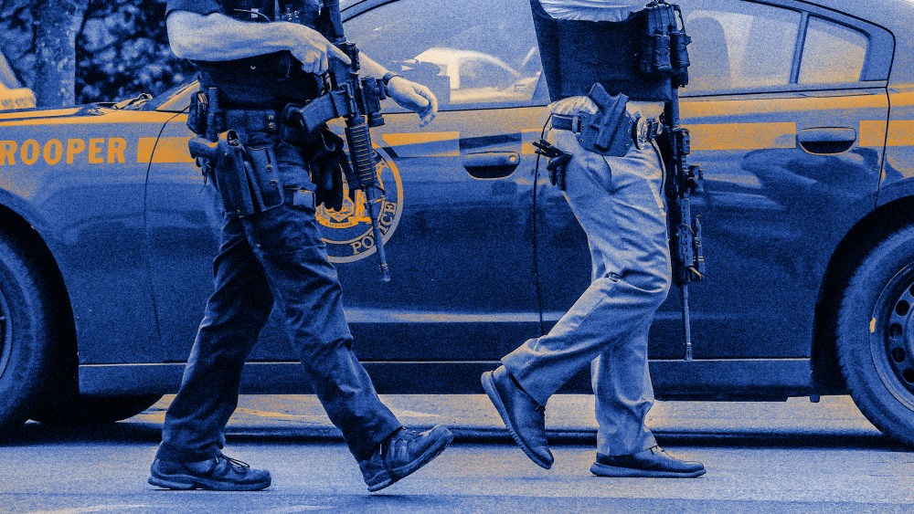Image: Close-up image of two armed police officers walking.