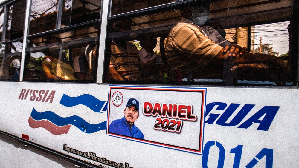 A man rides a bus with a Daniel Ortega campaign sticker on the side in Managua, Nicaragua on June 22, 2021.