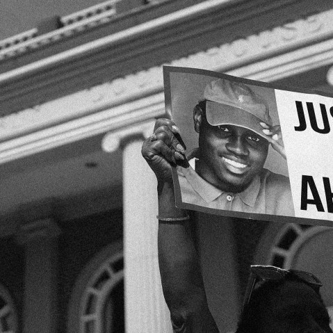 Image: A demonstrator holding a sign that reads, "Justice for Ahmaud"outside a courthouse.