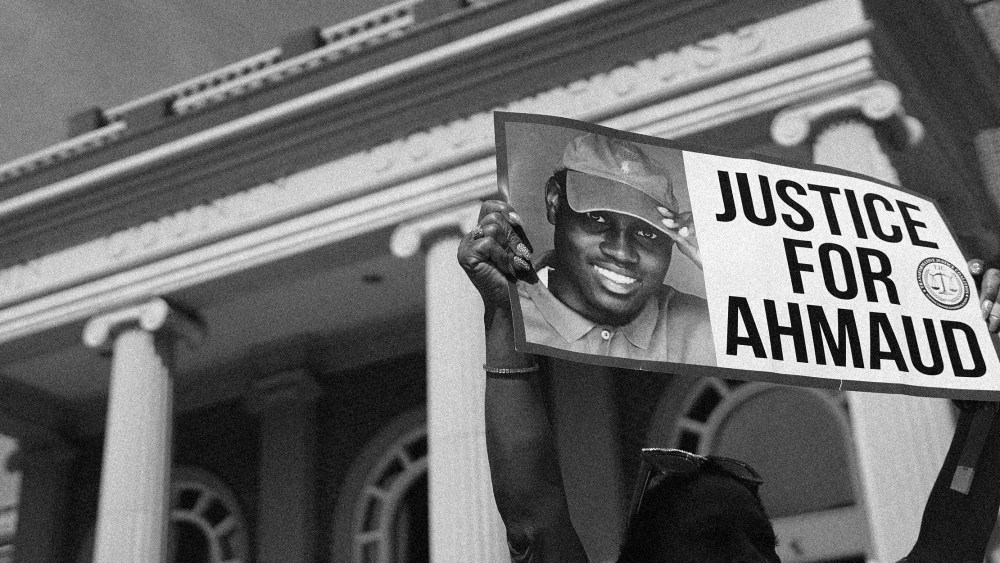 Image: A demonstrator holding a sign that reads, "Justice for Ahmaud"outside a courthouse.