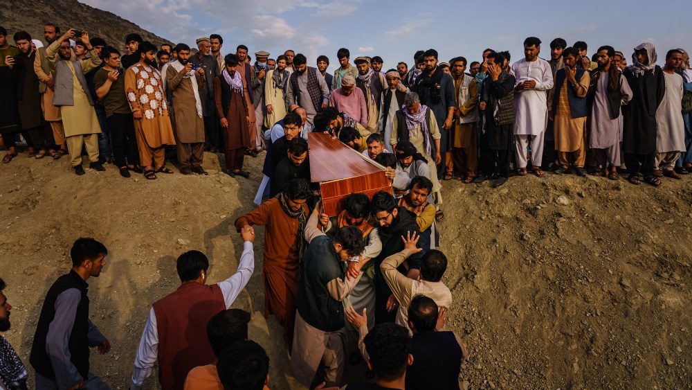 Image: Caskets being carried towards a gravesite at a mass funeral.